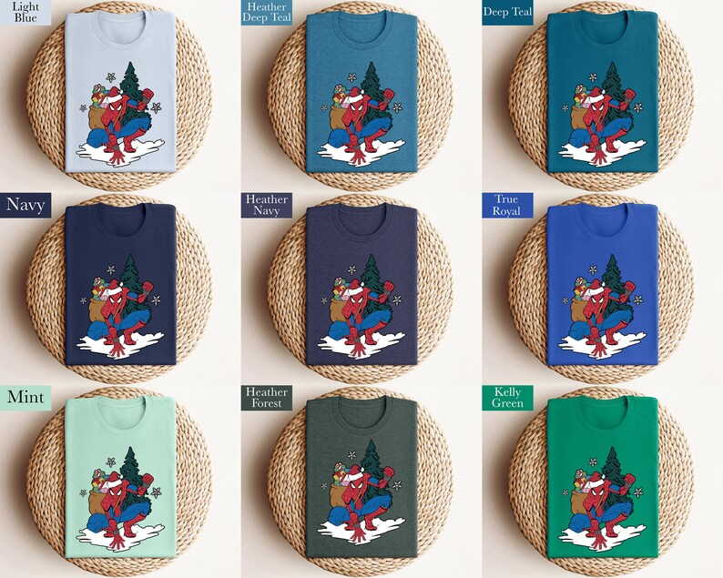 Puede incluir: Una colecci&oacute;n de camisetas en varios colores, cada una con un gr&aacute;fico de un superh&eacute;roe con gorro de Pap&aacute; Noel, llevando un saco de regalos y un &aacute;rbol de Navidad. Los colores incluyen azul claro, marino, verde azulado y verde.