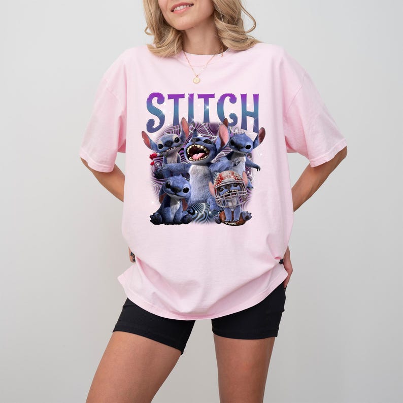 K&ouml;nnte beinhalten: Hellrosa T-Shirt mit einem Aufdruck der Figur Stitch aus dem Disney-Film Lilo & Stitch. Das Wort "STITCH" ist in gro&szlig;en, farbigen Buchstaben &uuml;ber der Figur gedruckt. Die Grafik enth&auml;lt mehrere Bilder von Stitch.