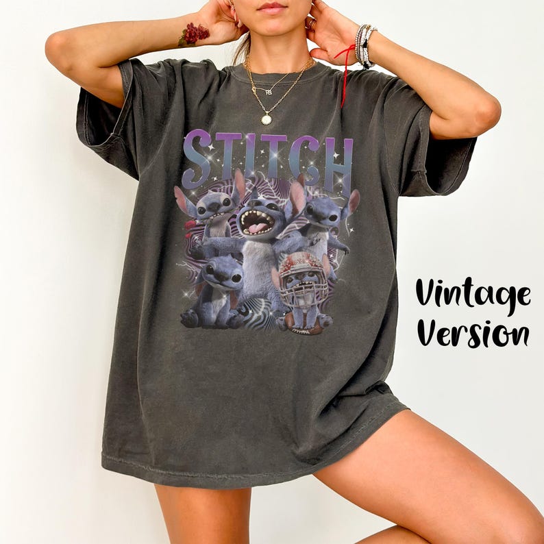 K&ouml;nnte beinhalten: Dunkelgraues T-Shirt mit einem Aufdruck der Figur Stitch aus Lilo & Stitch, mit dem Wort "STITCH" &uuml;ber dem Bild. Das Design zeigt mehrere Stitch-Charaktere in verschiedenen Posen. Die Worte "Vintage Version" sind auf der rechten Seite aufgedruckt.