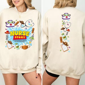 K&ouml;nnte beinhalten: Beiges Sweatshirt mit farbenfrohem Grafikdesign. Auf der Vorderseite steht "NURSE STORY" mit medizinischen Illustrationen. Die R&uuml;ckseite hat eine vertikale Anordnung &auml;hnlicher Grafiken. Das Sweatshirt besteht aus einem weichen Material.