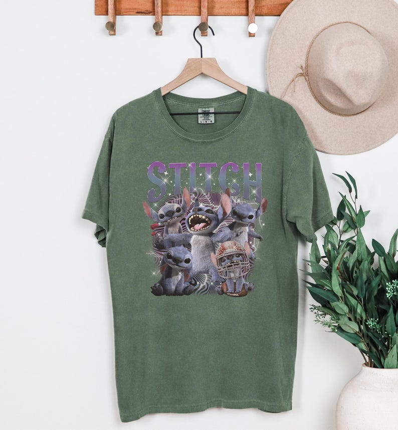 K&ouml;nnte beinhalten: Gr&uuml;nes T-Shirt mit einer Grafik der Figur Stitch aus dem Film Lilo & Stitch. Das Wort "STITCH" ist in einer lila, glitzernden Schrift &uuml;ber der Figur gedruckt. Das Bild enth&auml;lt mehrere Darstellungen von Stitch.