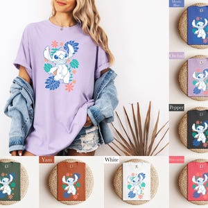 Puede incluir: Una camiseta de color lila claro con un personaje de dibujos animados y un dise&ntilde;o floral. La camiseta la lleva una persona, con otras camisetas en azul, morado, negro, verde, naranja, blanco y rojo, cada una con el mismo dise&ntilde;o.