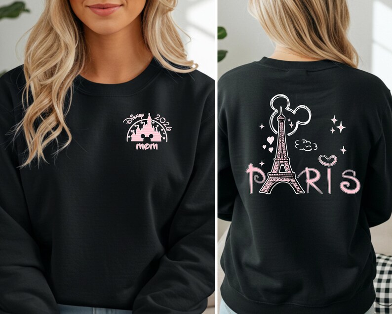 May include: Black sweatshirt with pink graphic designs. The front features a castle design with the text "Disney 2026 mom". The back displays the Eiffel Tower, Mickey Mouse ears, and the word "Paris".