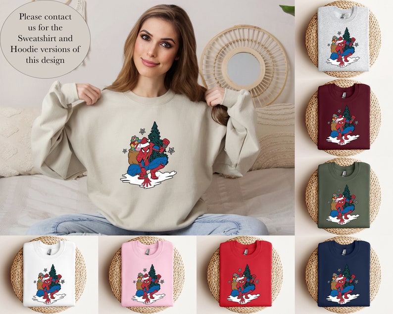 Puede incluir: Sudadera beige con un gr&aacute;fico colorido de un superh&eacute;roe con traje de Pap&aacute; Noel, llevando un &aacute;rbol de Navidad y regalos. Se muestran sudaderas adicionales en gris, burdeos, verde, blanco, rosa, rojo y azul marino. Texto en la imagen: "Please contact us for the Sweatshirt and Hoodie versions of this design."