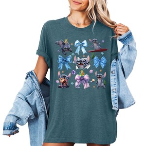 Puede incluir: Camiseta de color verde azulado con un dise&ntilde;o del personaje Stitch de Lilo & Stitch. El dise&ntilde;o incluye a Stitch en varias poses con lazos azules, conchas marinas y estrellas de mar. La camiseta tiene un corte holgado y mangas cortas.