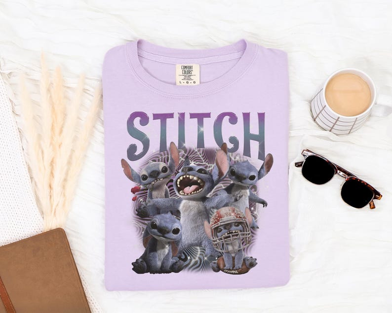 K&ouml;nnte beinhalten: Ein helllila T-Shirt mit dem Wort "STITCH" in lila aufgedruckt. Das T-Shirt zeigt eine Grafik der Figur Stitch aus dem Disney-Film Lilo & Stitch. Das Bild enth&auml;lt auch eine Sonnenbrille und eine Kaffeetasse.