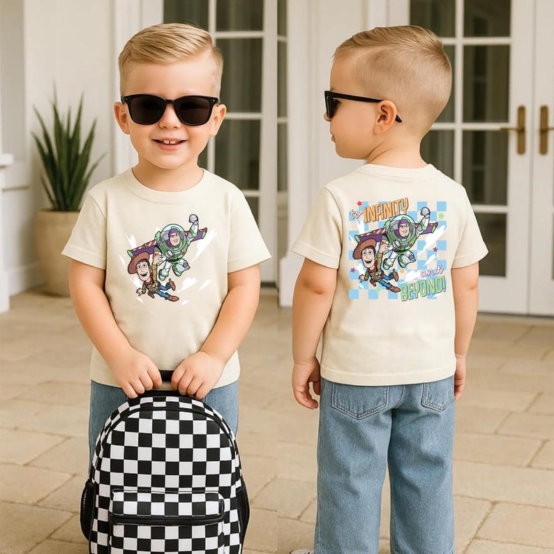 Puede incluir: Un ni&ntilde;o lleva una camiseta color crema con Buzz Lightyear y Woody de Toy Story. La camiseta tiene la frase "&iexcl;Hasta el infinito y m&aacute;s all&aacute;!" en la espalda. El ni&ntilde;o lleva vaqueros azules y una mochila a cuadros blancos y negros.
