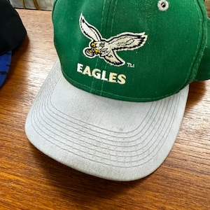 May include: Green and gray baseball cap with a white embroidered eagle and the word "EAGLES" on the front.