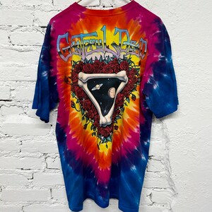 Puede incluir: Camiseta tie-dye con un dise&ntilde;o colorido que presenta una calavera con rosas y el texto "Grateful Dead" en la espalda.