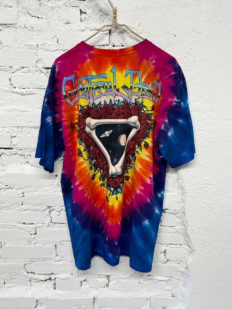 Puede incluir: Camiseta tie-dye con un dise&ntilde;o colorido que presenta una calavera con rosas y el texto "Grateful Dead" en la espalda.