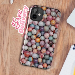 May include: A phone case with a colorful marble pattern. The case is designed for a phone with a camera bump. The case is on a wooden surface.