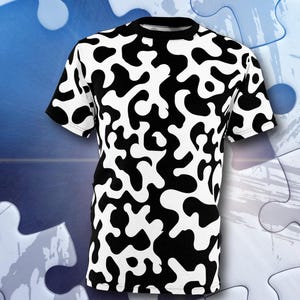 Könnte beinhalten: Ein kurzärmeliges T-Shirt mit einem schwarz-weißen abstrakten Muster. Das Design zeigt unregelmäßige, organische Formen auf weißem Hintergrund. Das Shirt hat einen Rundhalsausschnitt und wird auf blauem Hintergrund mit Puzzleteilen präsentiert.