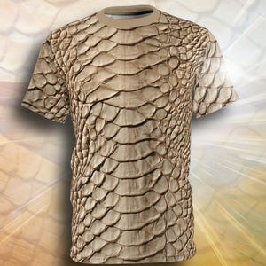 May include: A short-sleeved t-shirt featuring an all-over print of a realistic tan and brown snake skin pattern. The garment has a crew neckline and a straight hem, with the scale texture covering the entire front surface of the shirt.