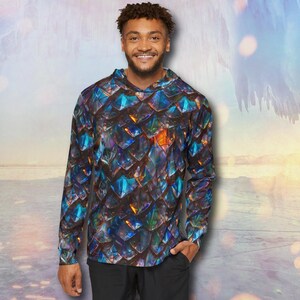 May include: A long-sleeved hooded shirt with a scale-like pattern in shades of blue, purple, and orange. The shirt has a unique design and is made of a comfortable material. The shirt is a great addition to any wardrobe.