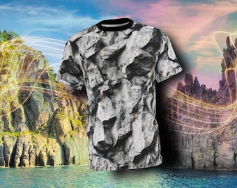 May include: A black and white t-shirt with a rock texture pattern. The shirt is photographed against a background of rocky cliffs and a blue sky with clouds.