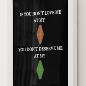 May include: A framed art print with the text "IF YOU DON'T LOVE ME AT MY" above an orange diamond shape, and "YOU DON'T DESERVE ME AT MY" above a green diamond shape. The frame is white, and the background is black.