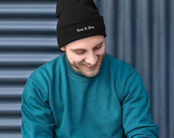 Può includere: Un berretto in maglia nero con il testo "Suck A Dick" ricamato in bianco sul risvolto anteriore. Il cappello è realizzato in materiale a coste e presenta un design con bordo ripiegato. Il testo è scritto in un semplice carattere bianco sans-serif.