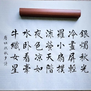 May include: Black ink calligraphy on white paper with the text "銀燭秋光冷畫屏輕羅小扇撲流螢天階夜色凉如水卧看牽牛織女星" written in traditional Chinese characters.