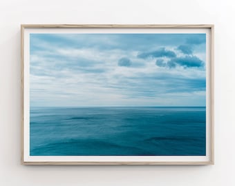 May include: A framed photograph of a blue ocean with a cloudy sky. The ocean is a deep blue color and the sky is a light blue color with white clouds.