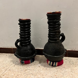 Peut inclure: Deux vases en céramique noire avec un motif en spirale texturé. Les vases sont décorés de tissu coloré à la base.