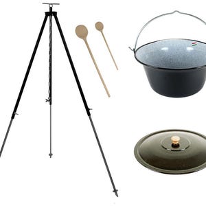 Könnte beinhalten: Ein schwarzer Dreibeinständer mit einer Kette und einem Haken zum Aufhängen eines Topfes über einem Feuer. Zwei Holzlöffel sind im Lieferumfang enthalten, sowie ein schwarzer Emailletopf mit Deckel.