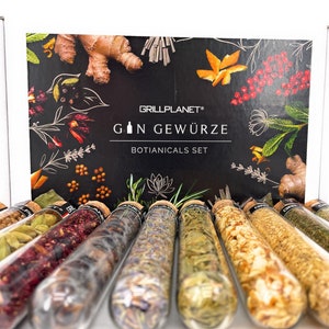 Könnte beinhalten: Ein Set mit 12 Glasröhrchen gefüllt mit verschiedenen getrockneten Kräutern und Gewürzen, beschriftet "Gin Gewürze Botanicals Set" auf einer schwarzen Box mit botanischem Design.