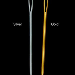 Op de afbeelding: Twee naalden, een zilveren en een gouden, worden getoond tegen een zwarte achtergrond. De zilveren naald staat links en de gouden naald rechts. Het woord "Silver" staat onder de zilveren naald en het woord "Gold" onder de gouden naald.