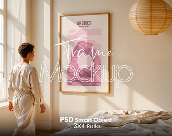 May include: A framed poster with a pink and white illustration of a mountain range and the text "Arches National Park". The poster is hanging on a beige wall in a room with a bed and a window.