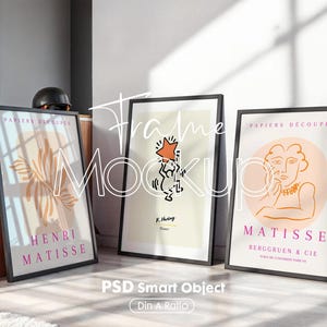 Puede incluir: Tres impresiones artísticas enmarcadas apoyadas contra una pared. Las impresiones presentan diseños de arte moderno, incluyendo una impresión de Matisse y una pieza de Keith Haring. Los marcos son negros y las impresiones tienen una estética limpia y minimalista. El texto "Frame Mockup" es visible.