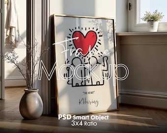 May include: A gold framed poster with a white background and a black and white illustration of three people holding a red heart. The text "THE HEART" and "K. Haring" are printed below the illustration.