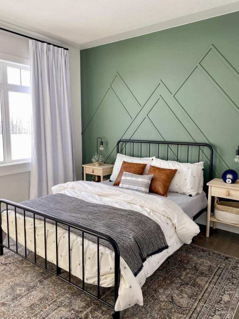 May include: A black metal bed frame with a white and gray patterned duvet and a gray throw blanket. The bed is in a bedroom with a green wall featuring a geometric pattern.