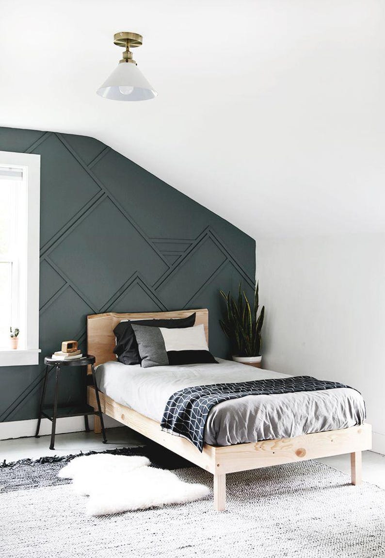 May include: A wooden bed frame with a gray and white patterned blanket and pillows. The bed is in a bedroom with a dark green wall with geometric shapes.