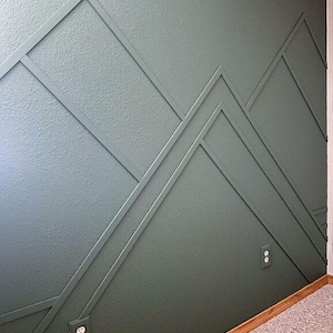 May include: A wall painted in a dark green color with a geometric pattern of white lines forming a mountain range design. Two electrical outlets are visible on the wall.