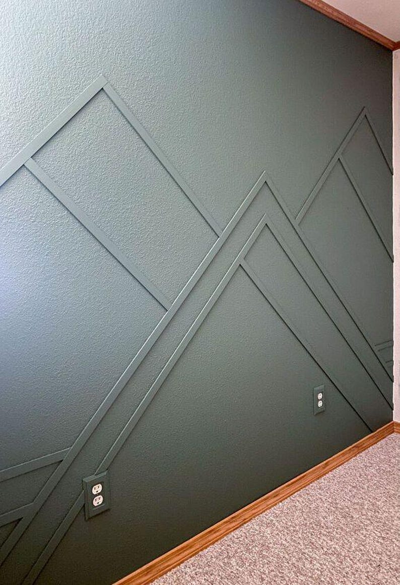 May include: A wall painted in a dark green color with a geometric pattern of white lines forming a mountain range design. Two electrical outlets are visible on the wall.