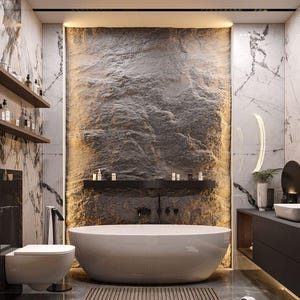May include: A modern bathroom with a large, white, oval-shaped bathtub. The wall behind the tub features a textured, dark gray stone design, illuminated by warm lighting. The room includes marble-patterned walls, dark wood shelves, and a toilet.