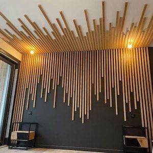 May include: A room with a wooden slat ceiling and a wall covered in vertical wooden slats. The wall is painted black and the slats are a light brown colour. There are two small black side tables with shelves and a white ladder in the corner of the room.