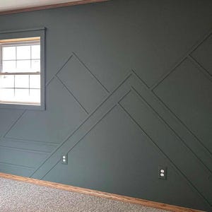 May include: A dark gray wall with a geometric pattern of raised lines creating a mountain range design. The wall has two electrical outlets and a window with white trim.