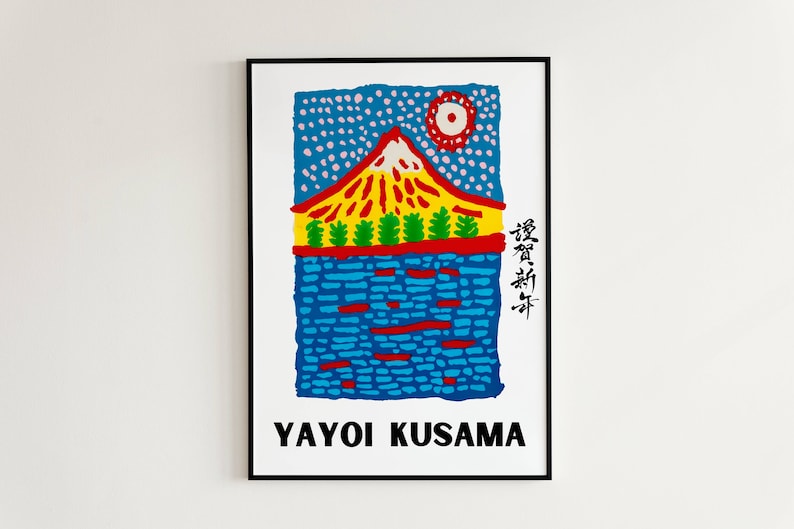 May include: A framed art print featuring a colorful illustration of a mountain with a red and yellow peak, green trees, and blue water. The sky is blue with white dots and a red sun. The artist's name, Yayoi Kusama, is printed at the bottom.
