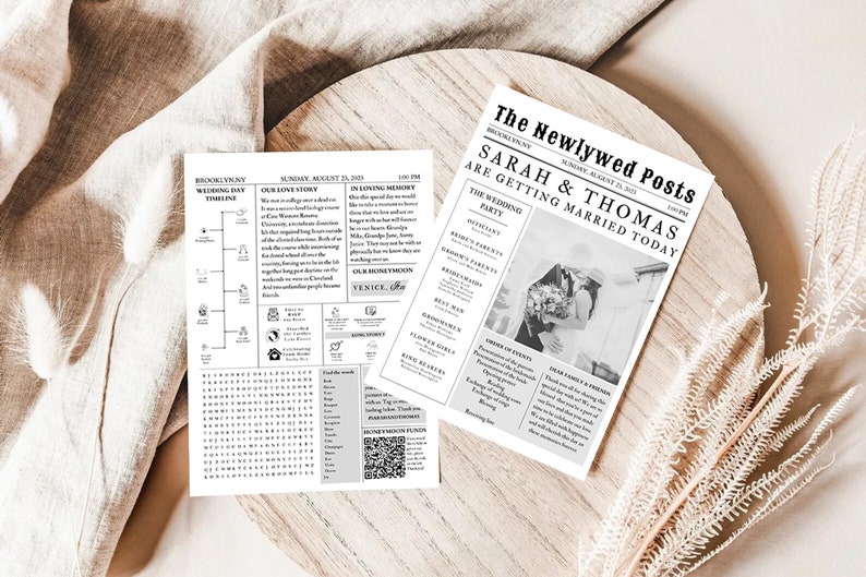 K&ouml;nnte beinhalten: Zwei schwarz-wei&szlig; Hochzeitszeitungsdrucke. Einer zeigt eine Zeitleiste und ein Wortsuchr&auml;tsel, der andere eine Schlagzeile mit der Aufschrift "SARAH & THOMAS HEIRATEN HEUTE". Die Drucke befinden sich auf einer Holzoberfl&auml;che mit dekorativen Elementen.
