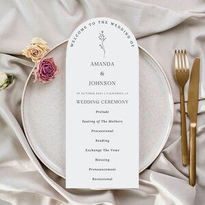 Może przedstawiać: Elegancka karta programu ceremonii ślubnej z łukowatym wierzchem, z nazwiskami "Amanda & Johnson" i datą "22 października 2024". Program wymienia wydarzenia ceremonii. Karta znajduje się na białym talerzu ze złotymi sztućcami i suszonymi kwiatami.