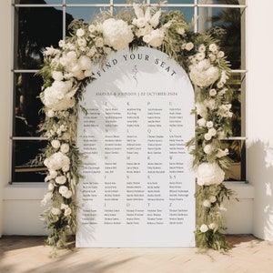 May include: A wedding seating plan with the text "FIND YOUR SEAT" and guest names. The names are listed alphabetically. The sign is adorned with white flowers and foliage. The wedding date is 22 October 2024.