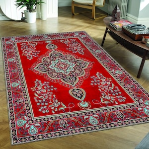 May include: A red rug with a detailed floral pattern in black, white, and blue. The rug has a central medallion with a paisley design.