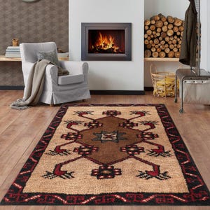 May include: A rectangular area rug with a geometric pattern in shades of brown, beige, and red. The rug features a central diamond shape with intricate designs and a black border. The rug is placed on a wooden floor.
