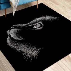 May include: Black rectangular rug featuring a detailed white illustration of a lion's face. The design highlights the eye, nose, and mouth, creating a striking contrast against the dark background. A decorative accent for any room.