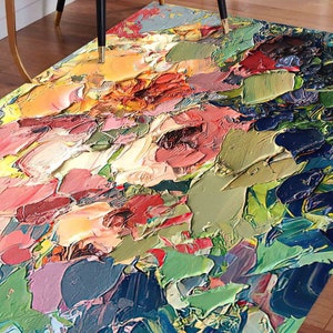 Può includere: Un tappeto rettangolare con un design floreale astratto. Il tappeto presenta spessi tratti di pennello in tonalità di rosa, rosso, verde, giallo e blu, creando un aspetto strutturato e artistico. Il tappeto è posato su un pavimento in legno.