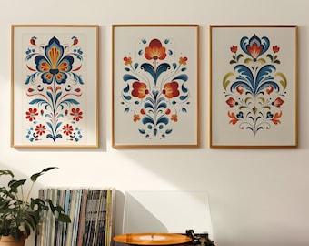 May include: Three framed prints with colorful floral designs. Each print features a different floral pattern with red, blue, and green colors. The prints are hung on a white wall above a record player and a shelf with records.
