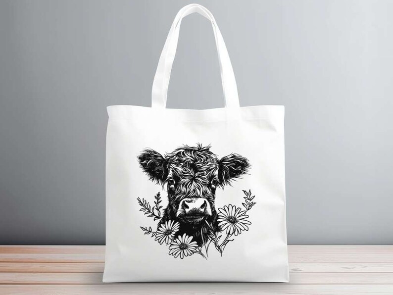 May include: A white tote bag with a black and white illustration of a cow's head with flowers. The cow is looking directly at the viewer.
