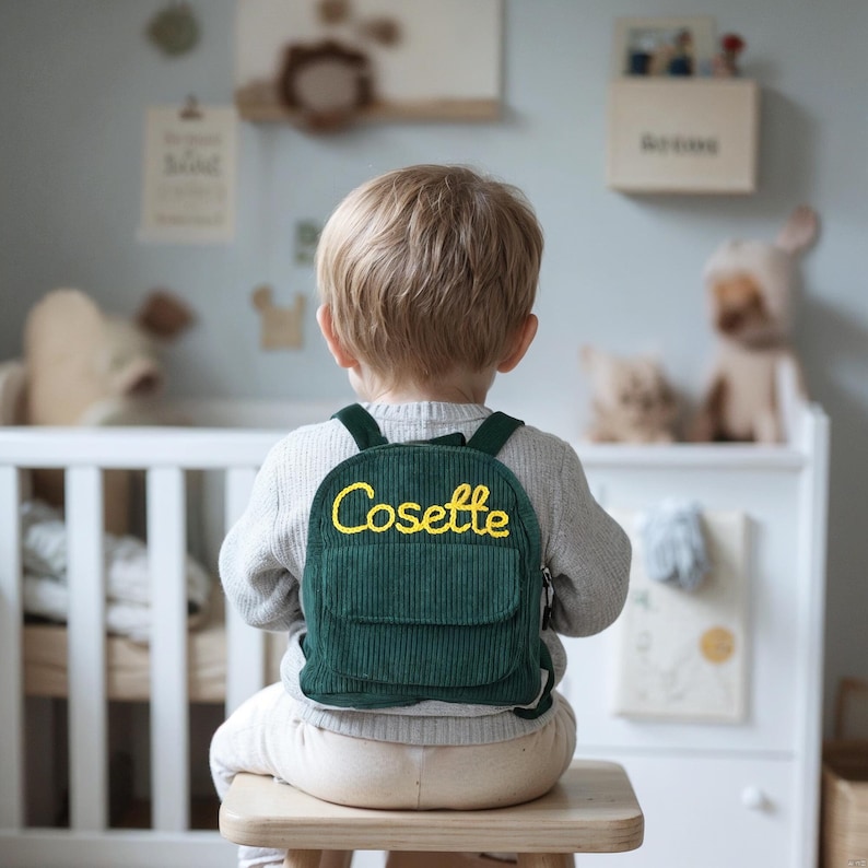 May include: A green corduroy backpack with yellow embroidered text that reads "Cosette".