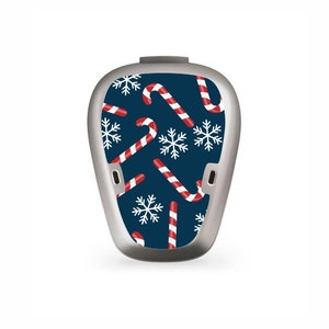 Puede incluir: Una piel de color azul y blanco para un audífono. El patrón presenta bastones de caramelo rojos y blancos y copos de nieve blancos.