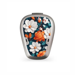 Puede incluir: Una funda plateada con un diseño floral con flores blancas y rosas naranjas sobre un fondo azul oscuro.